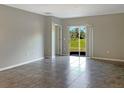 Well-lit living room featuring tile floors, neutral paint, and sliding glass doors leading to the backyard at 14853 Crescent Rock Dr, Wimauma, FL 33598