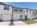 Modern townhome featuring an attached garage, a neutral color scheme, and a well-maintained lawn at 11826 Sylvia St, Dade City, FL 33525