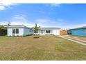 Inviting light blue home showcasing fresh landscaping, a well-manicured lawn, and a modern metal roof at 511 Sharon Cir, Port Charlotte, FL 33952