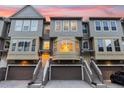 Townhomes with garages, stairs, and beige and gray color palette glow against a colorful sunset sky at 4324 Spinnaker Cove Ln, Tampa, FL 33615