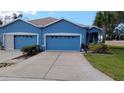 Charming blue home featuring a driveway and attached garage, complete with well-maintained landscaping at 12209 Putter Green Ct, New Port Richey, FL 34654