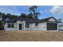 New construction displays a charming one-story home with modern windows, black trim, and a two-car garage at 2607 Seagull Ln, North Port, FL 34286