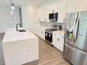 A modern kitchen features white cabinets, stainless steel appliances, black hardware, and a center island at 2607 Seagull Ln, North Port, FL 34286