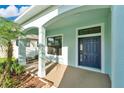 Inviting front porch with a navy blue door, decorative columns, and well-manicured landscaping at 7108 Harvest Glen Ln, Riverview, FL 33578