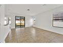 Spacious open living room with tile floors, neutral paint, and natural light from the sliding glass doors at 7108 Harvest Glen Ln, Riverview, FL 33578
