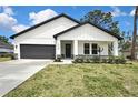 Charming home featuring a modern white exterior, black trim, well-kept lawn, and manicured landscaping at 10383 Lear St, Spring Hill, FL 34608