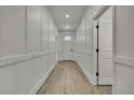 Hallway featuring wood-look flooring, crisp white trim, modern wainscoting detail, and a glass paneled front door at 10383 Lear St, Spring Hill, FL 34608