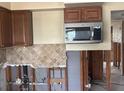 Kitchen with brown cabinets, tile backsplash, and stainless steel microwave at 411 Shore E Dr, Oldsmar, FL 34677
