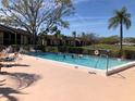 Outdoor swimming pool with people swimming, surrounded by a patio area and well-maintained landscaping at 6211 Timber Lake Dr # B4, Sarasota, FL 34243