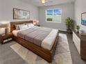 Modern bedroom with wood bed frame, soft rug, and natural light from a large window at 9793 Rally Spring Loop, Wesley Chapel, FL 33545