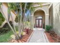 Inviting home entrance with a brick walkway, lush greenery, and a stylish arched doorway at 5802 Hatteras Palm Way, Tampa, FL 33615