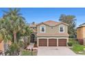 Spacious two-story home featuring a three-car garage, a tile roof, and a paver driveway at 5802 Hatteras Palm Way, Tampa, FL 33615