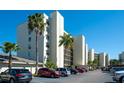 A low angle exterior view of the condos showcasing the parking area and palm trees at 1000 Cove Cay Dr # 5E, Clearwater, FL 33760