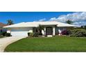 Charming home with a lush green lawn, complemented by colorful flowers and an oversized two car garage at 1727 Waxwing Cir, Venice, FL 34293