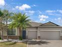 Charming single-story home featuring a three-car garage, brick driveway, stone accents and mature landscaping at 10009 Celtic Ash Dr, Ruskin, FL 33573