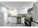 Bright kitchen featuring white cabinets, stainless appliances, granite counters, and wood-look floors at 10952 61St Ave, Seminole, FL 33772