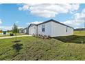 Exterior shot of a white single-story home with a green lawn and landscaping in the front yard at 31632 Malbec Dr, Brooksville, FL 34602