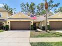 Charming townhome with two-car garage, manicured lawn, and an American flag at 8539 Sandpiper Ridge Ave, Tampa, FL 33647