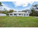 Attractive home with a white exterior, metal roof and well-manicured lawn at 18526 Sweetbay Ln, Dade City, FL 33523