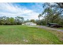 Expansive yard featuring a white home with metal roof, shed, and vehicle storage at 18526 Sweetbay Ln, Dade City, FL 33523