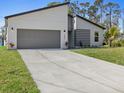 Modern home with gray accents, a well-kept lawn, and a spacious driveway leading to a two-car garage at 24299 Kingsway Cir, Punta Gorda, FL 33983