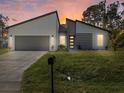 Beautiful single-Gathering home at dusk featuring modern design, a two-car garage, and green lawn at 24520 Kingsway Cir, Punta Gorda, FL 33983