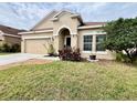 Inviting exterior with tan stucco, a two-car garage, and well-maintained lawn and landscaping at 724 Parker Den Dr, Ruskin, FL 33570