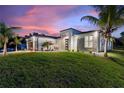 A modern home accentuated by palm trees, complemented by vibrant lawn and concrete driveway at 24470 Kingsway Cir, Punta Gorda, FL 33983