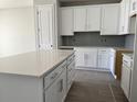 Modern kitchen features new white cabinets, gray backsplash, gray wood-look tile floors, and large kitchen island at 7268 Deer Valley Circle, Tampa, FL 33635