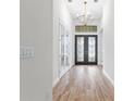 Elegant foyer featuring wood floors, a modern chandelier, and ornate glass double doors at 5516 Madrigal Way, Apollo Beach, FL 33572