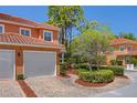 Two-story villa featuring an attached garage, brick driveway, and tropical landscaping at 2353 Max Ct, New Port Richey, FL 34655