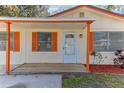 Close up front exterior featuring a white front door, orange shutters, and a small porch at 4046 Las Vegas Dr, New Port Richey, FL 34653
