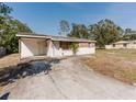 A single-story home featuring a carport, a partially bricked facade, and a small palm tree at 1825 134Th St, Largo, FL 33778