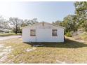 A back view of a white single-story home with two windows and green space around it at 1825 134Th St, Largo, FL 33778