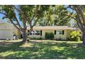 Inviting one-story home featuring manicured lawn, mature trees and neutral exterior at 1825 Alberta Dr, Clearwater, FL 33756