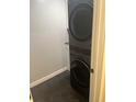 Laundry room with stacked front-load washer and dryer unit and modern finishes at 15168 Chamberlain Blvd, Port Charlotte, FL 33953