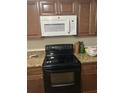 Well-equipped kitchen features dark wood cabinets, granite counters, and modern black appliances at 744 Myrtle Ave, Venice, FL 34285