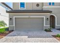 Two-car garage of a tan home with a paver driveway and well manicured front yard at 12654 Oak Hill Way, Parrish, FL 34219