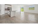 Open living space with tile flooring connecting the kitchen with a view of the backyard at 31622 Malbec Ln, Brooksville, FL 34602