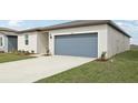 Exterior view showcasing the driveway and well-maintained lawn and blue garage door at 31673 Wild Grape Sw Ln, Brooksville, FL 34602