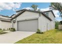 Contemporary home featuring a spacious two-car garage, well-manicured lawn, and modern design elements at 3824 Radiant Mountain Dr, Plant City, FL 33565