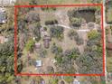 Expansive aerial view of a property with a pond, trees and multiple buildings within the parcel at 3634 Apfel Rd, Wesley Chapel, FL 33543