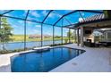 Stunning pool under a screened enclosure overlooking a lake and green space, and with an outdoor fireplace at 6243 Plateau Ct, Bradenton, FL 34203