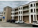 Exterior shot of a condo building with multiple balconies and cars parked in front at 8111 Lakewood Main St # 207, Lakewood Ranch, FL 34202