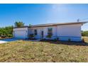 Charming single-story home featuring a two-car garage, manicured lawn, and a light and bright facade at 13089 Xavier Ave, Port Charlotte, FL 33981