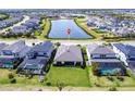 Aerial view of home showing landscaped yard, community pond, and screened in patios at 16524 Paynes Mill Dr, Bradenton, FL 34211