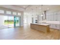 Modern kitchen with a large island, stainless steel appliances, and sliding glass doors to the outdoor space at 5013 Sea Branch Ave, Apollo Beach, FL 33572