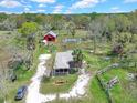 Wide aerial perspective showcasing a house, red barn, pond, and lush greenery, with a car parked nearby at 8123 Double Branch Rd # 1, Tampa, FL 33635