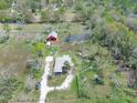Expansive aerial shot of a property featuring a house, barn, pond, and verdant landscape, under a sunny sky at 8123 Double Branch Rd # 1, Tampa, FL 33635