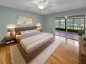 Relaxing main bedroom with balcony access, light walls and hardwood floors and modern bed set at 13516 Palmwood Ln, Tampa, FL 33618